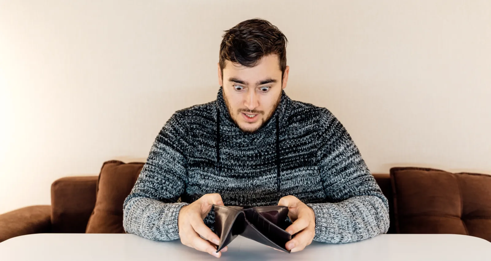 Foto de una persona jóven mirando consternado la billetera