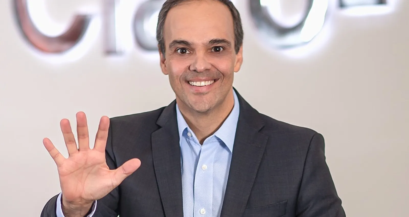 Foto de una persona saludando a la cámara anunciando el número 5