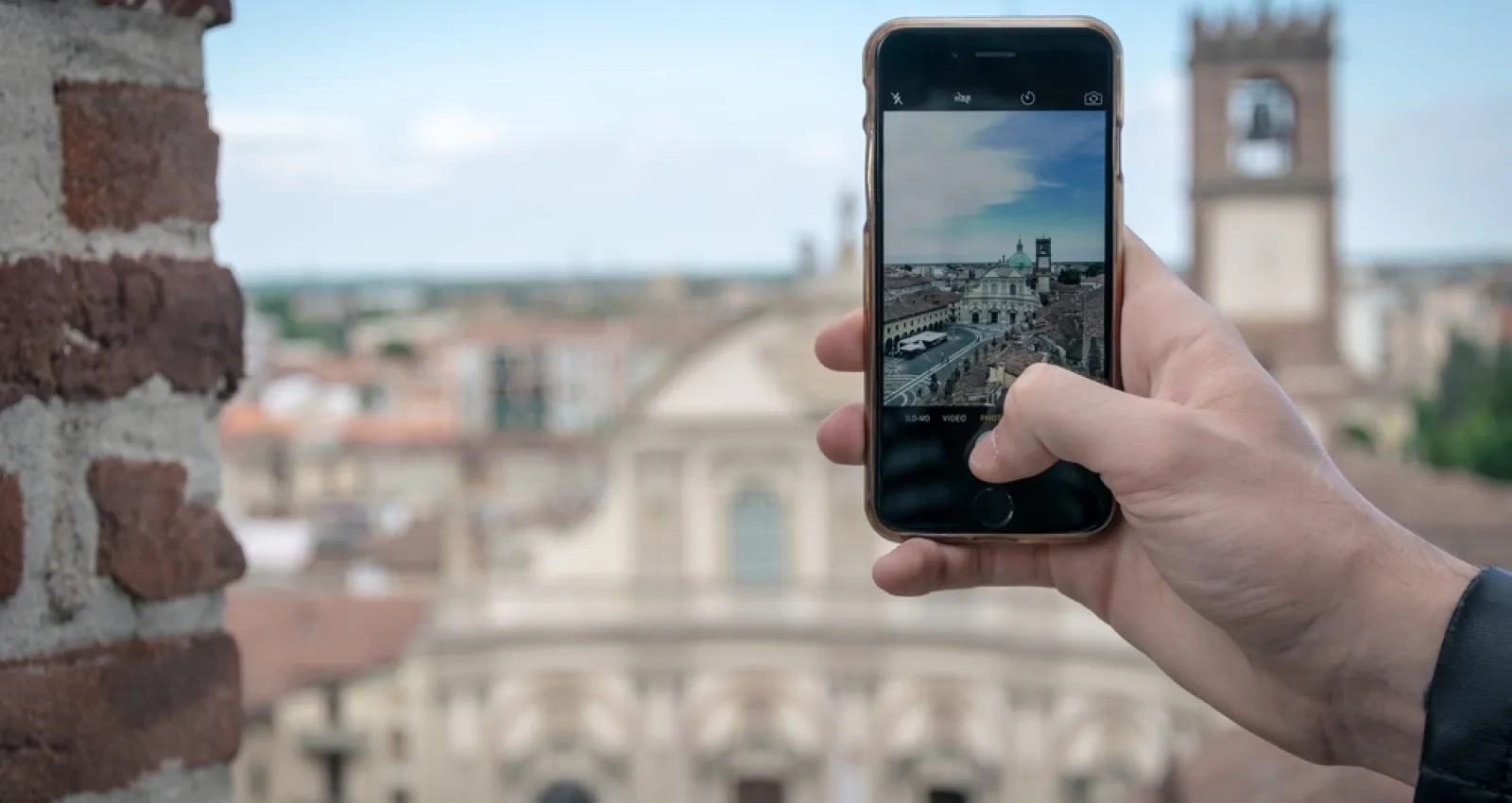Foto de una persona tomando una fotografia con el celular y el fondo de una ciudad europea