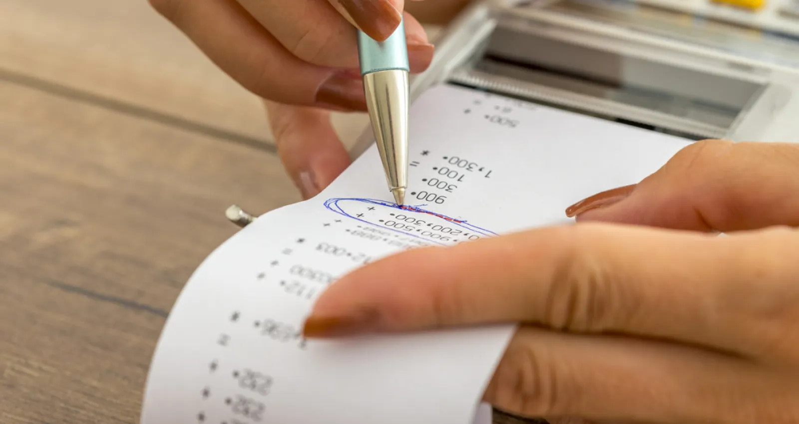 Foto de una persona utilizando un bolígrafo y escribiendo sobre un recibo