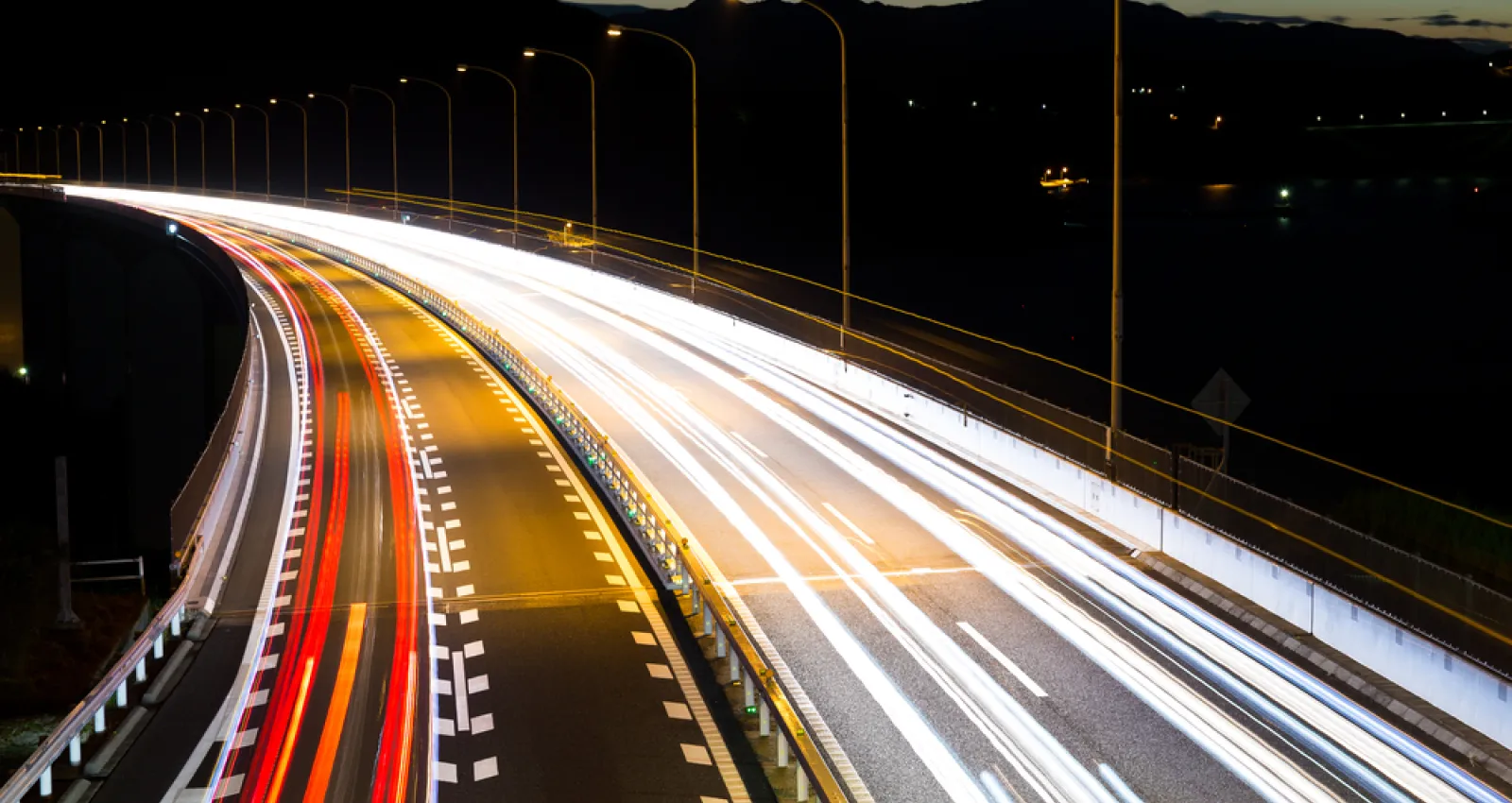 Foto de una vía con efecto de cámara, los carros se ven como luces de varios colores