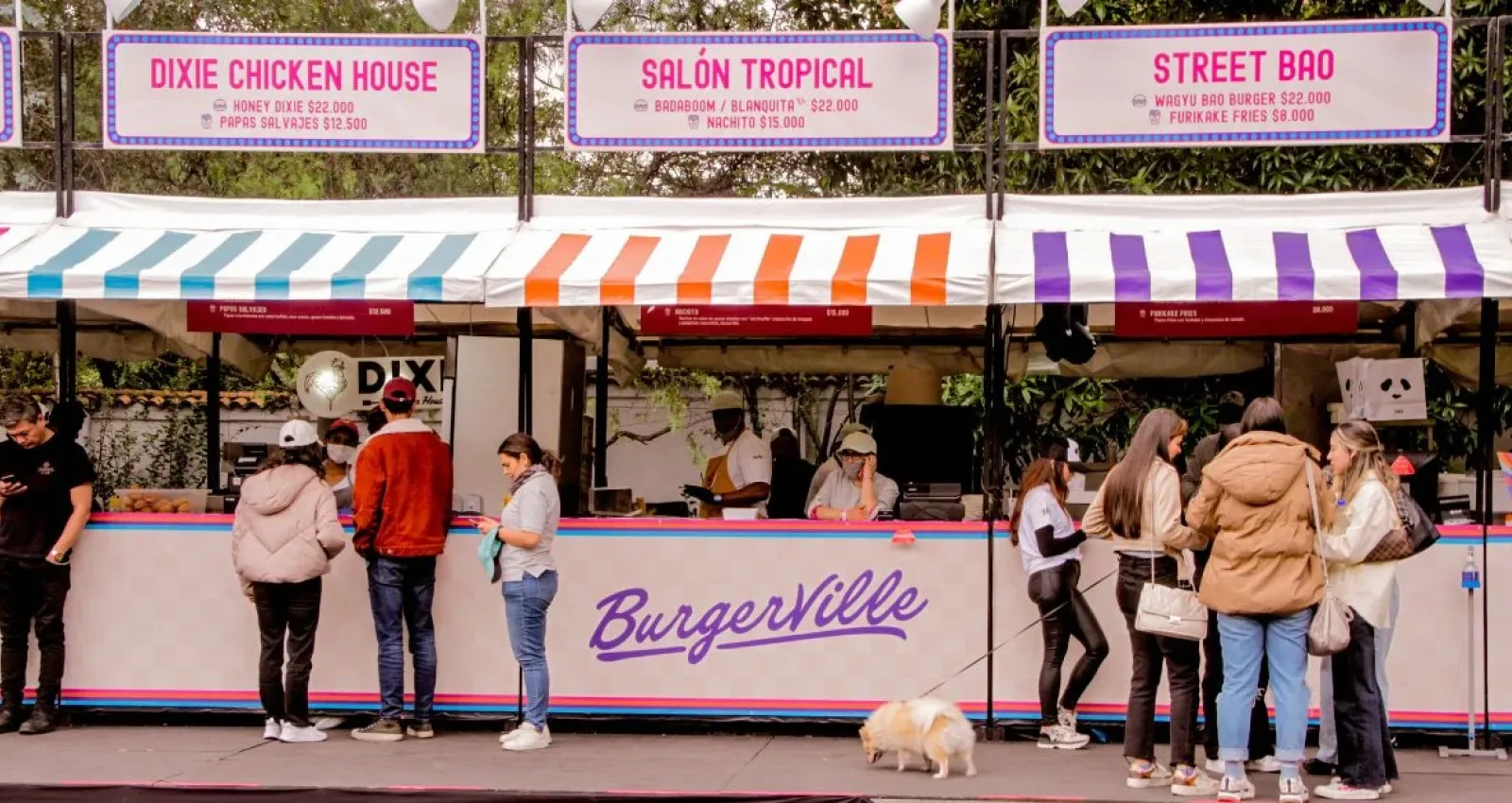 Foto de varias personas haciendo fila frente a unos locales de colores pastel