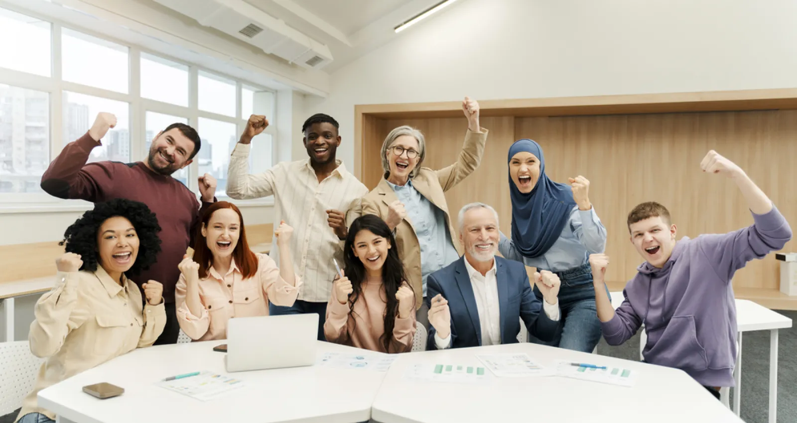 Foto de varias personas levantando la mano y sonriendo a la cámara