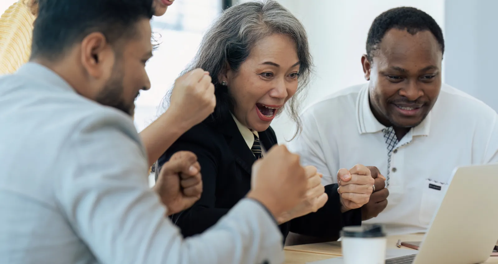 Foto de varias personas reunidas celebrando frente al computador