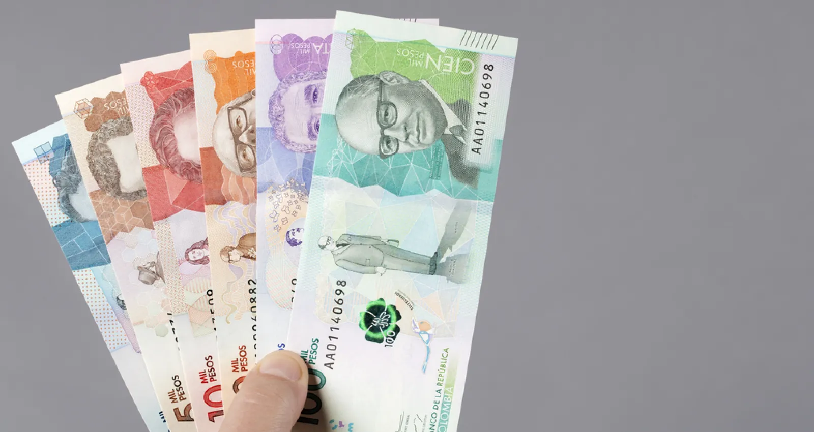 Foto de varios billetes colombianos en la mano de una persona