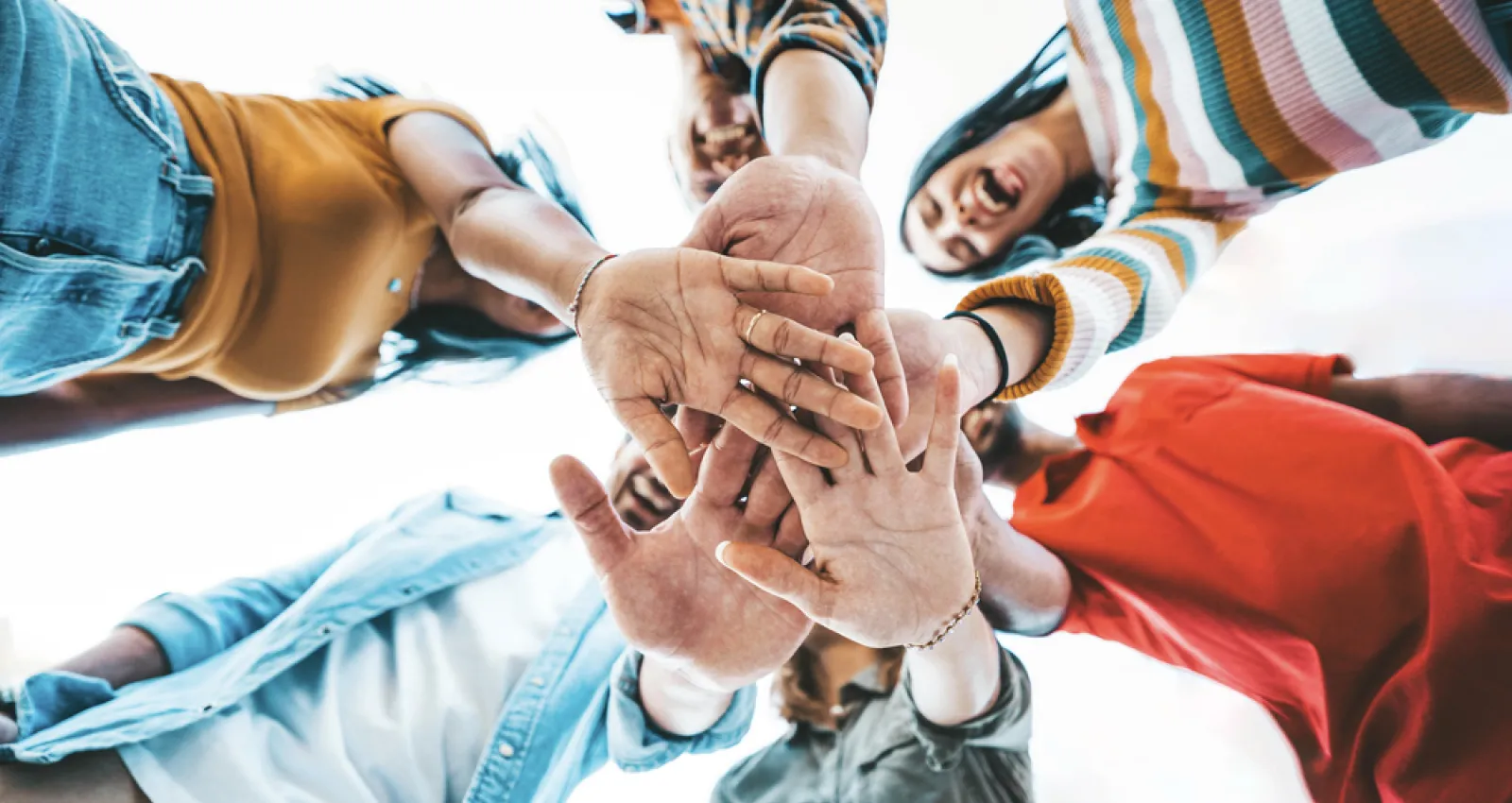 Foto de varios jovenes juntando sus manos en la mitad