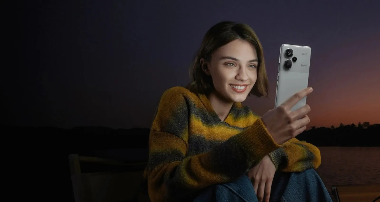 Fotografia de una mujer revisando un celular gris con un atarceder de fondo