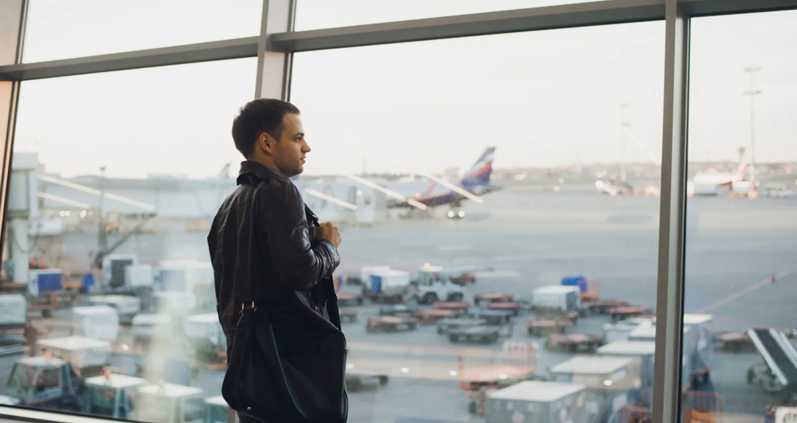 Hombre con traje negro mirando por la ventan de un aeropuerto
