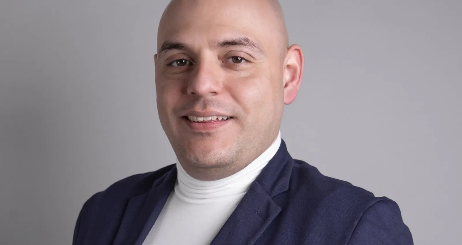 Hombre mirando a la cámara con blazer azul y camiseta blanca
