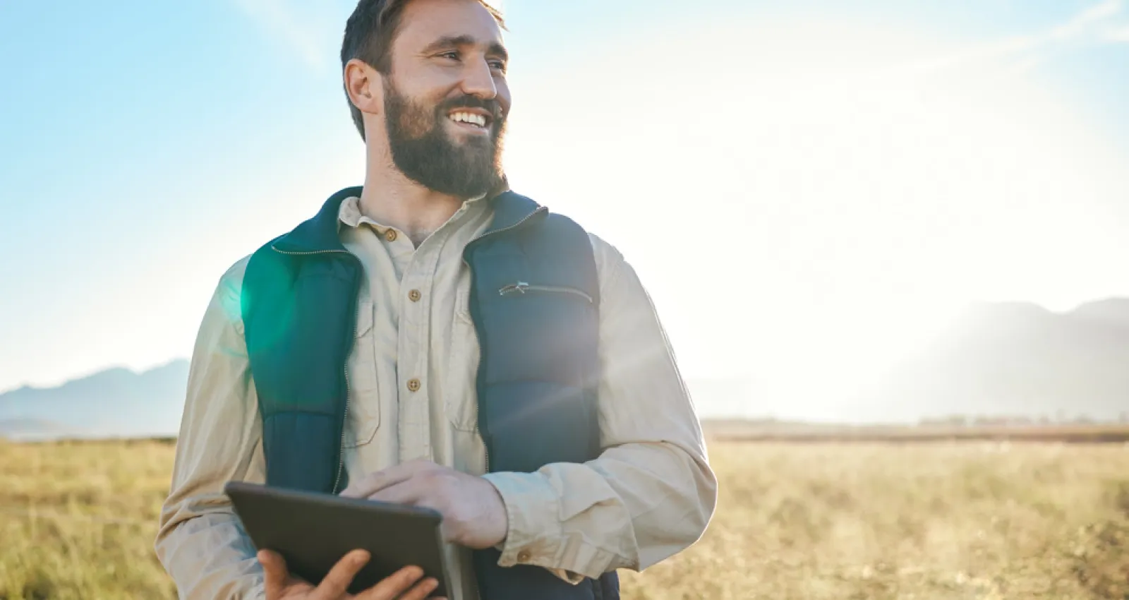 Hombre mirando el horizonte hacía la cámara con un paisaje rural