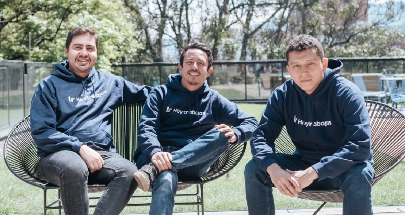 Tres jóvenes sentados, sonriendo a la cámara