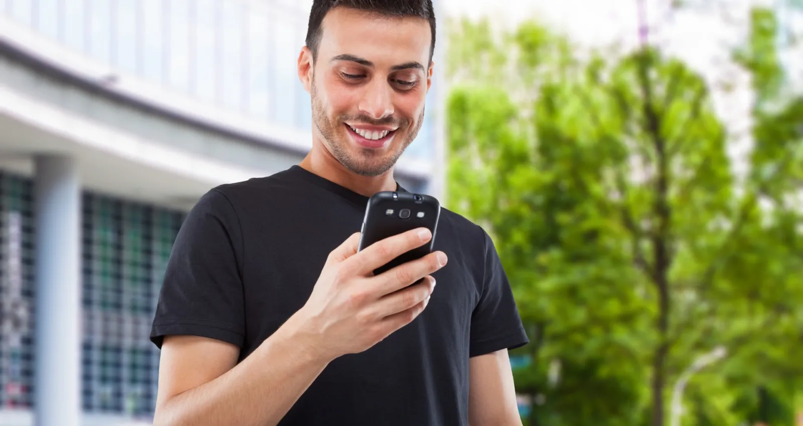 Foto de un hombre mirando al celular mientras sonrie