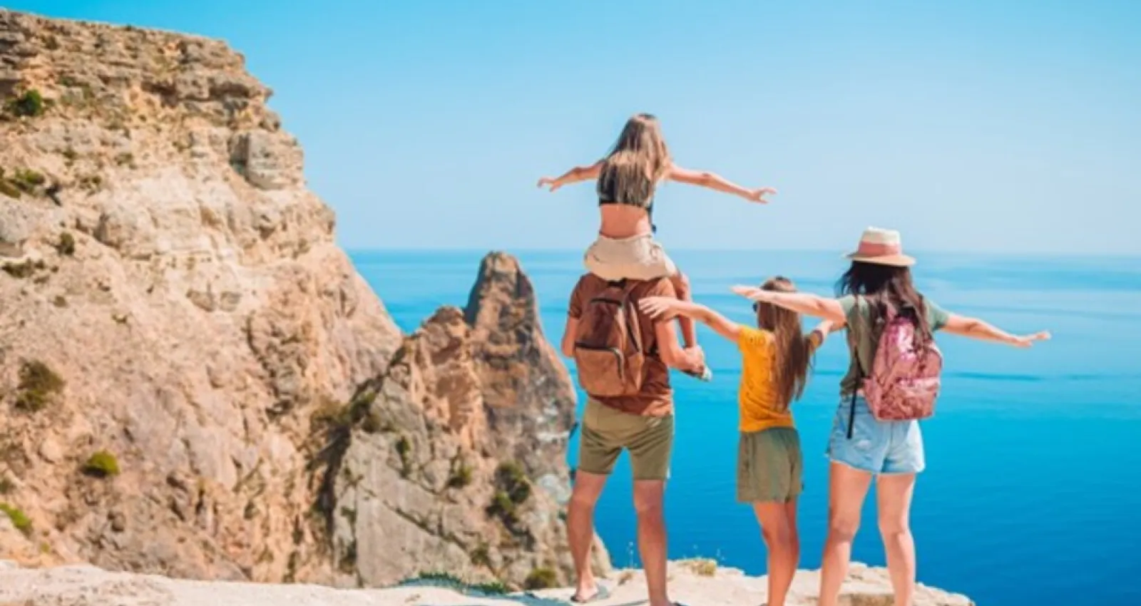 Imagen de una familia mirando al mar con un sol a sus espaldas