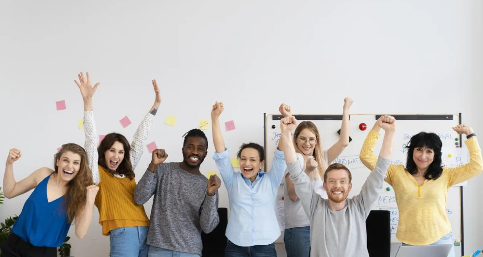 Foto de personas alzando las manos y sonriendo en sus oficinas
