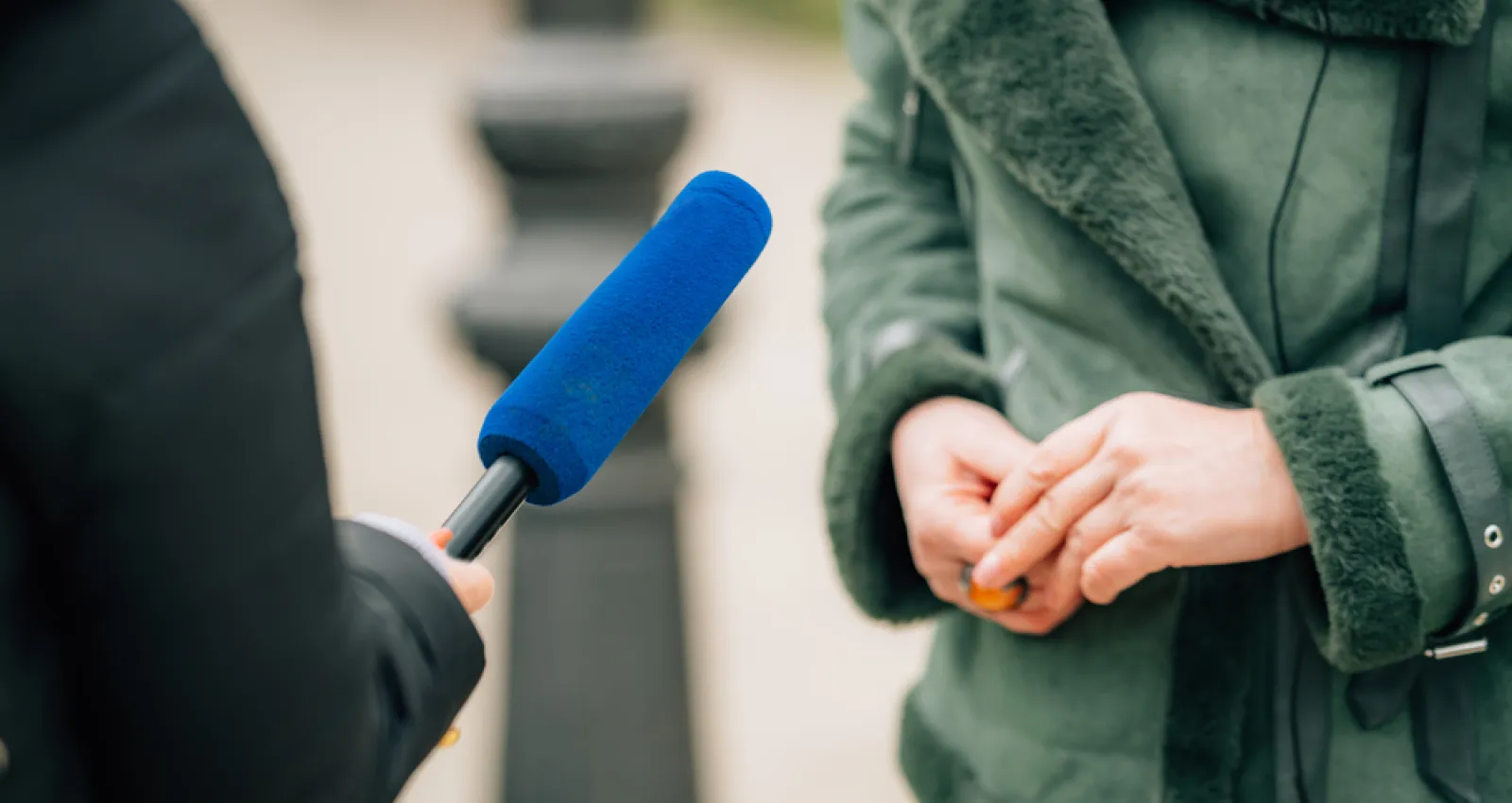 Foto de una persona con un micrófono azul entrevistando