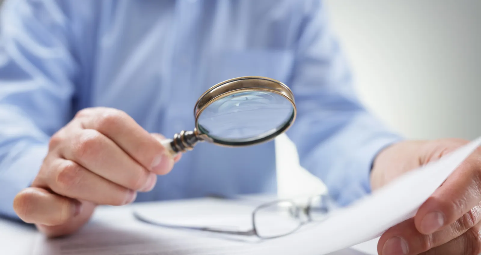 foto de una persona leyendo un documento con lupa