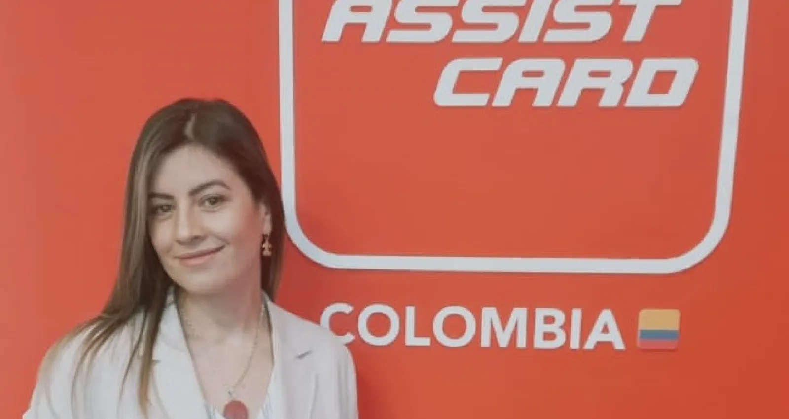 Foto de una mujer trigueña sonriendo a la cámara con un fondo que dice: Assist Card