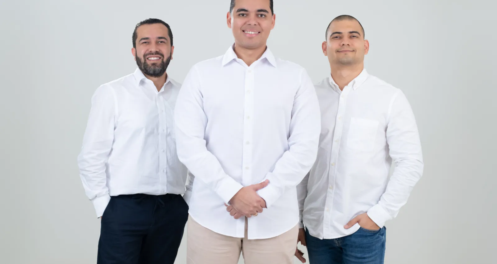 Fotografía de tres hombres con camiseta blanca mirando a la cámara