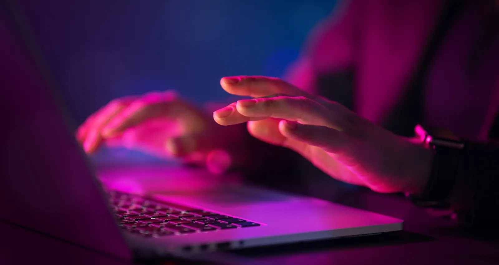 Manos sobre un computador portatil, foto con efecto morado 