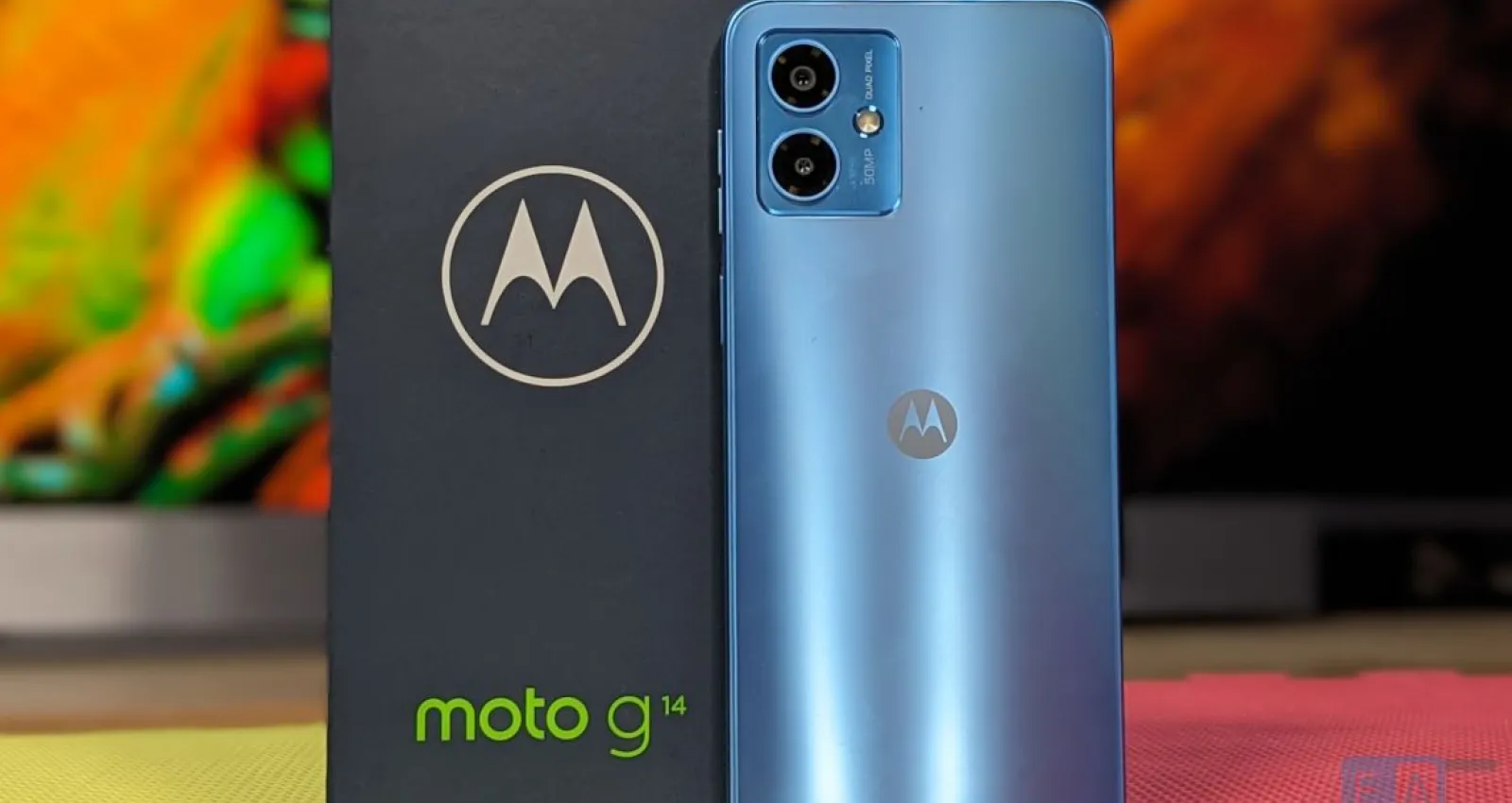Foto de motorola, celular azul claro con una caja nega de fondo