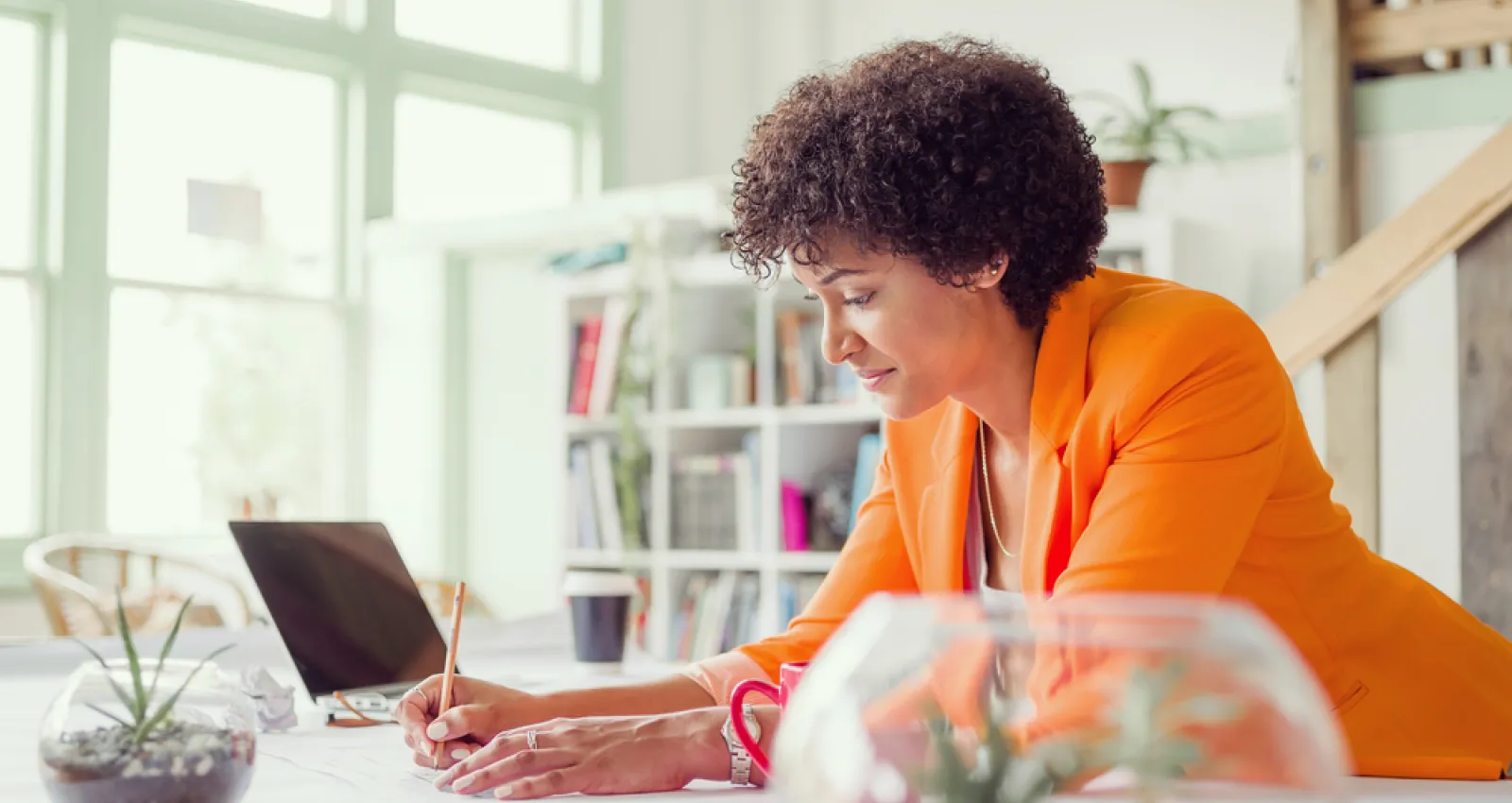 Mujer con blazer naranja mirando el computador