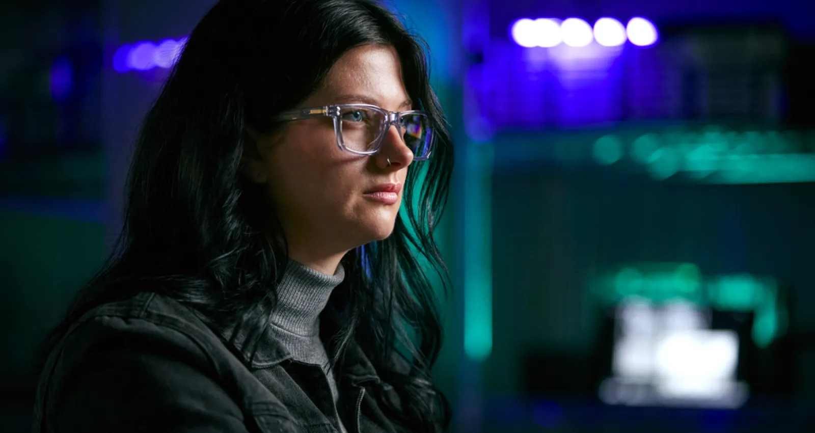 Mujer con gafas de perfil, pelo negro, viendo una pantalla