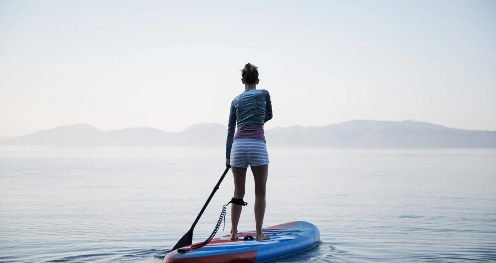 Mujer encima de una tabla en un lago