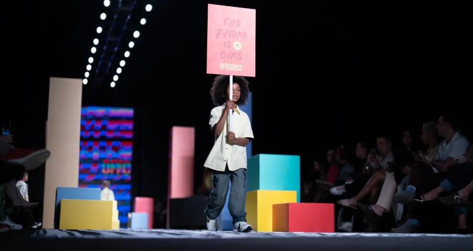 Niño caminando por una pasarela con un cartel encima