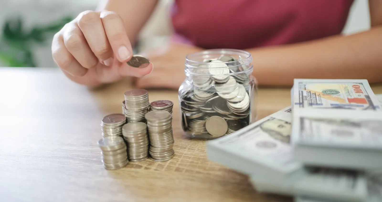 Persona recopilando monedas y billetes sobre una mesa