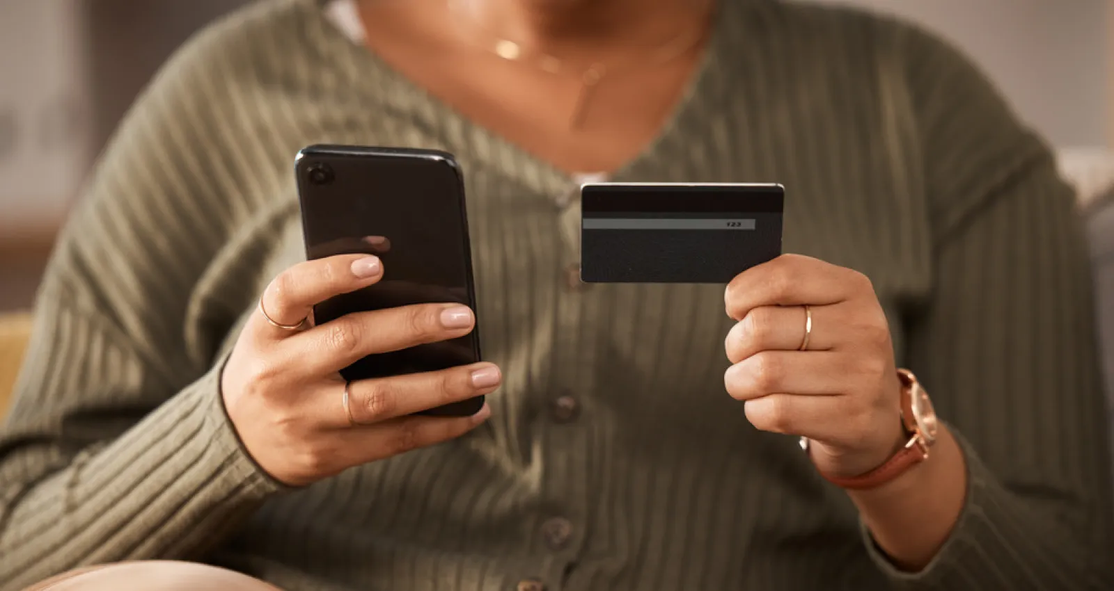 Persona sosteniendo una tarjeta en una mano y un celular en la otra