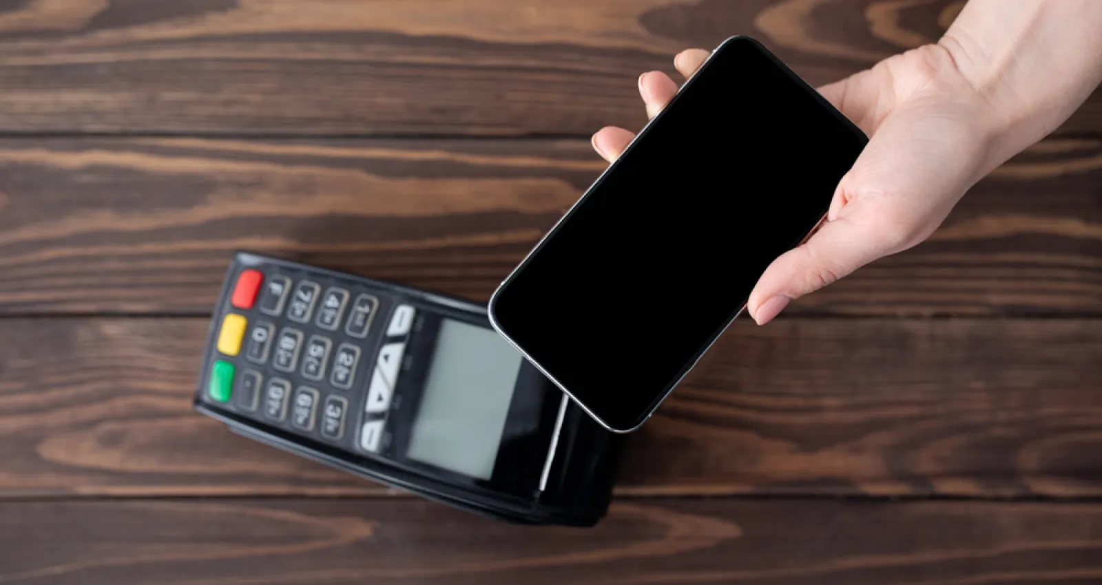 Representación de un datáfono con un celular encima, simulando un pago en línea