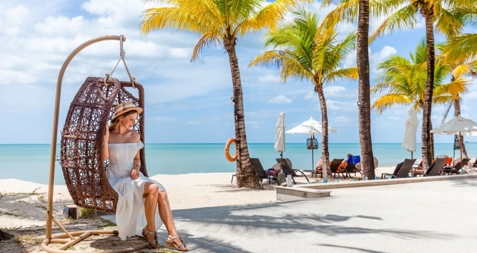 Mujer ubicada en una silla de playa con palmeras al fondo