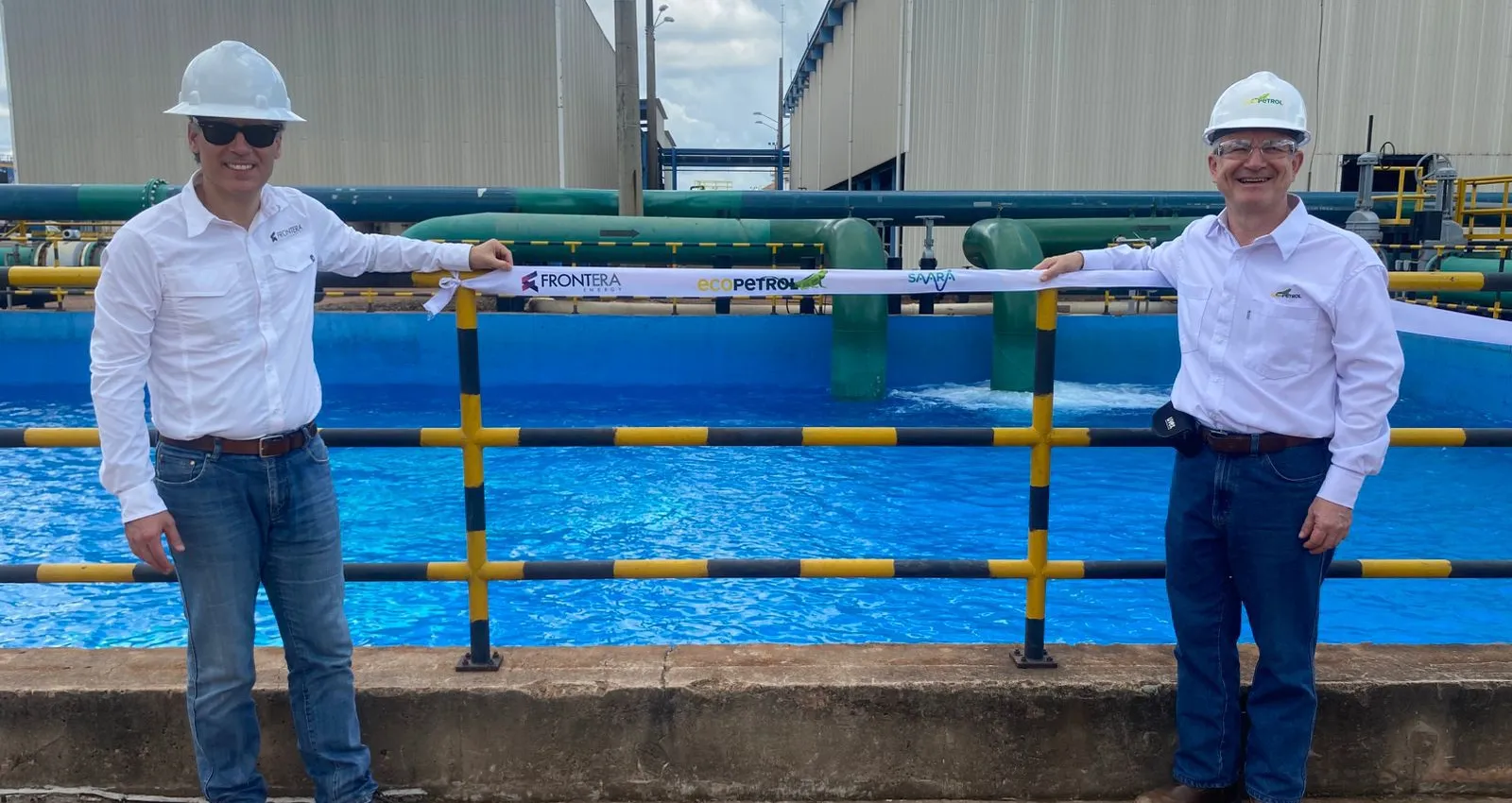 foto de dos personas frente a una planta de tratamiento de agua con camiseta blanca