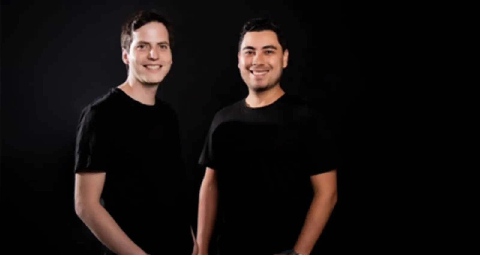 Foto de dos hombres con camiseta negra sonriendo a la cámara