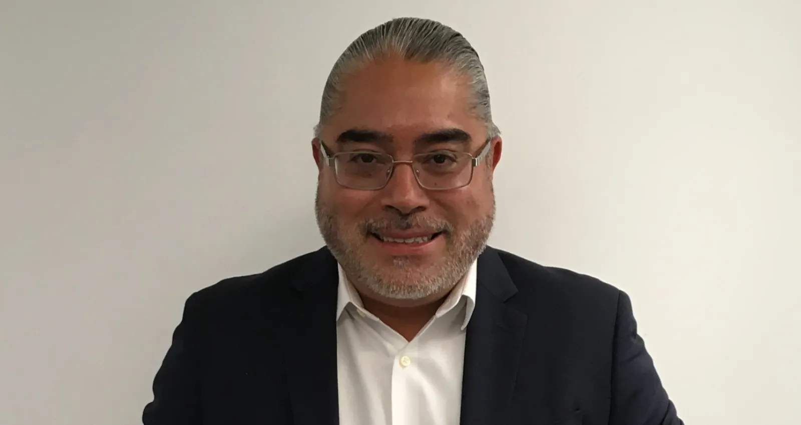Foto de un señor con gafas blancas, mirando a la cámara con pelo hacía a trás