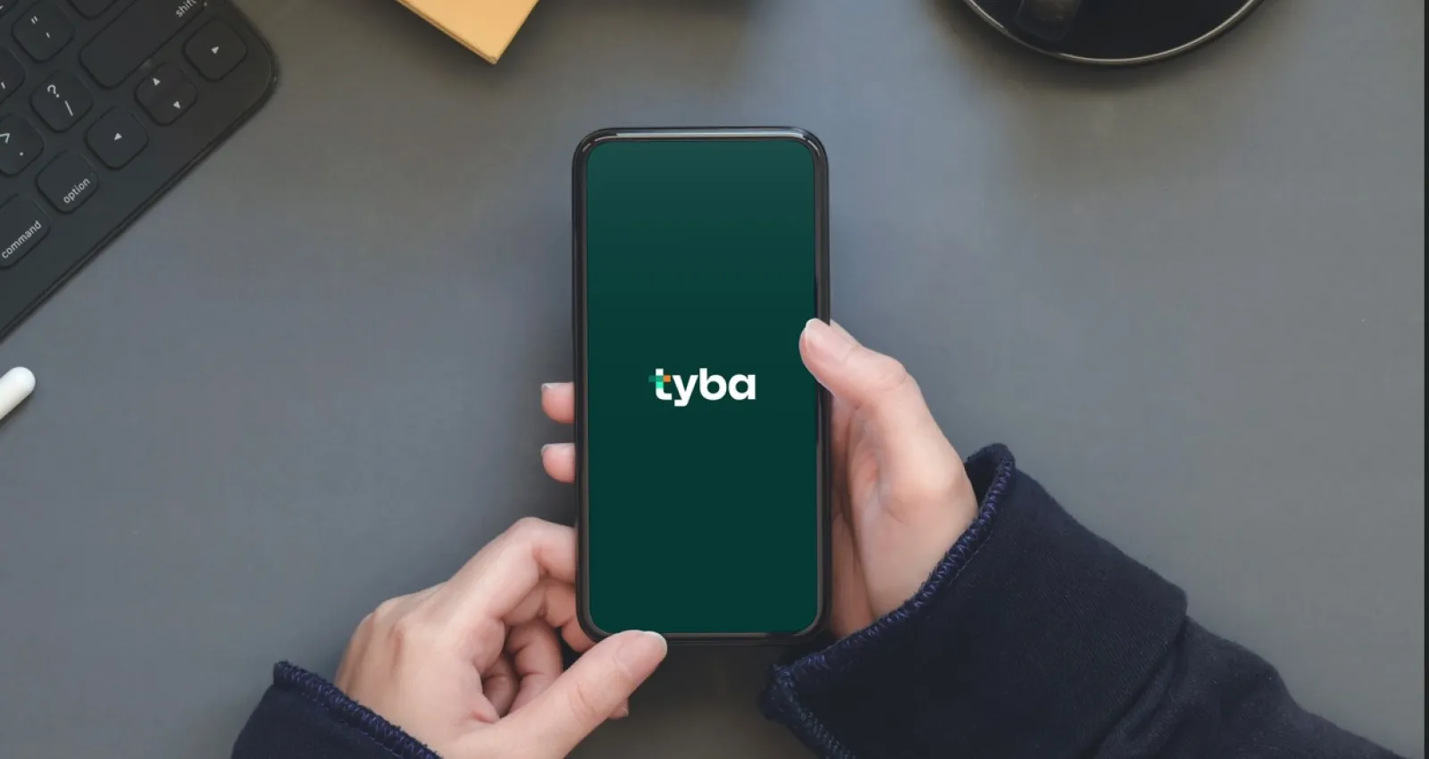 foto de una persona tomando un celular donde aparece la palabra tyba