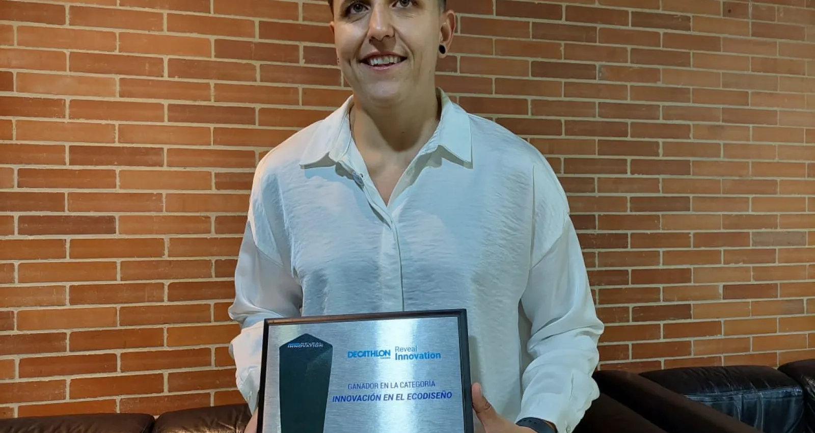 Foto de una mujer con el reconocimiento en la mano