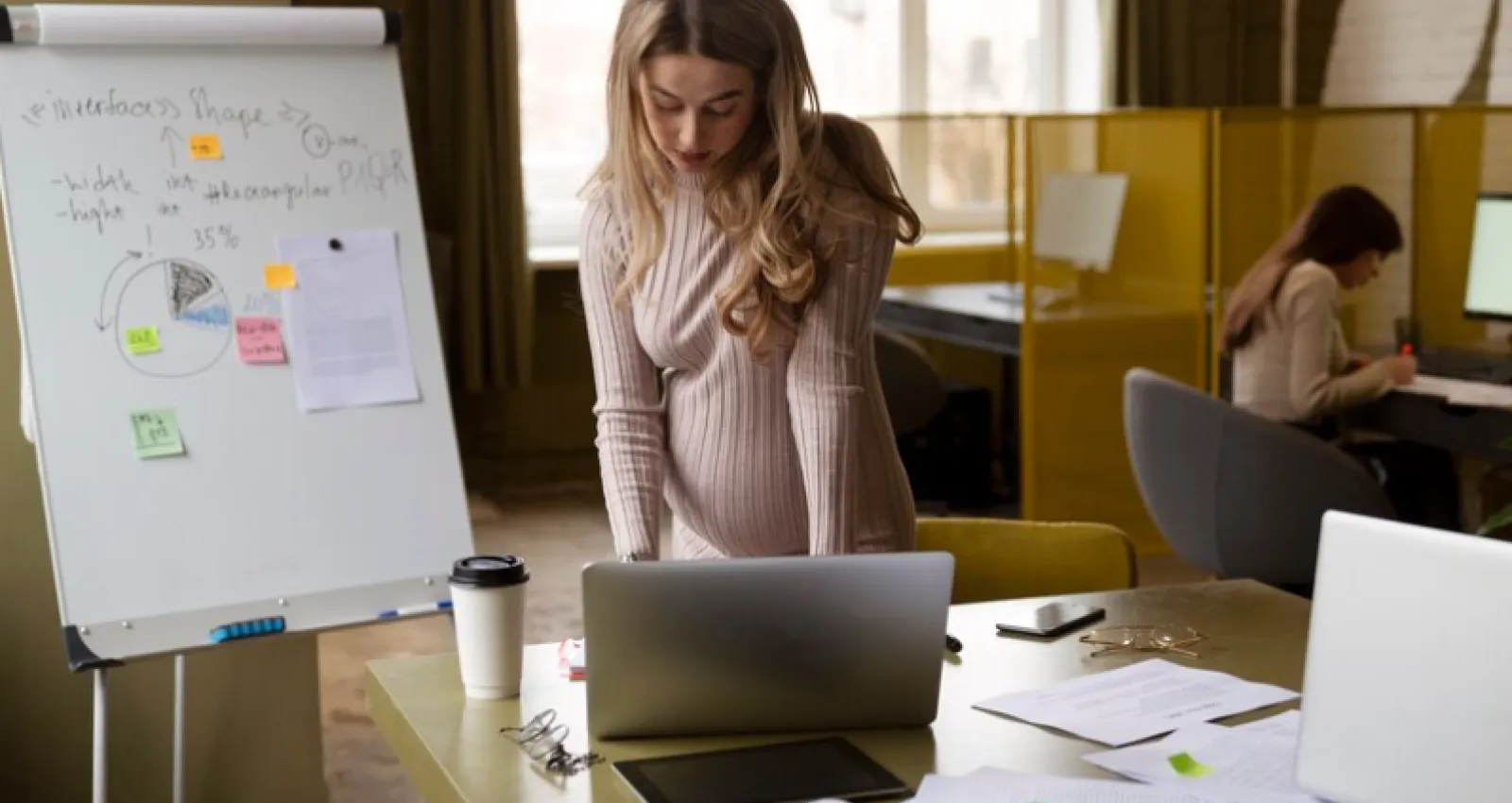 una mujer embarazada con su laptop en una agencia