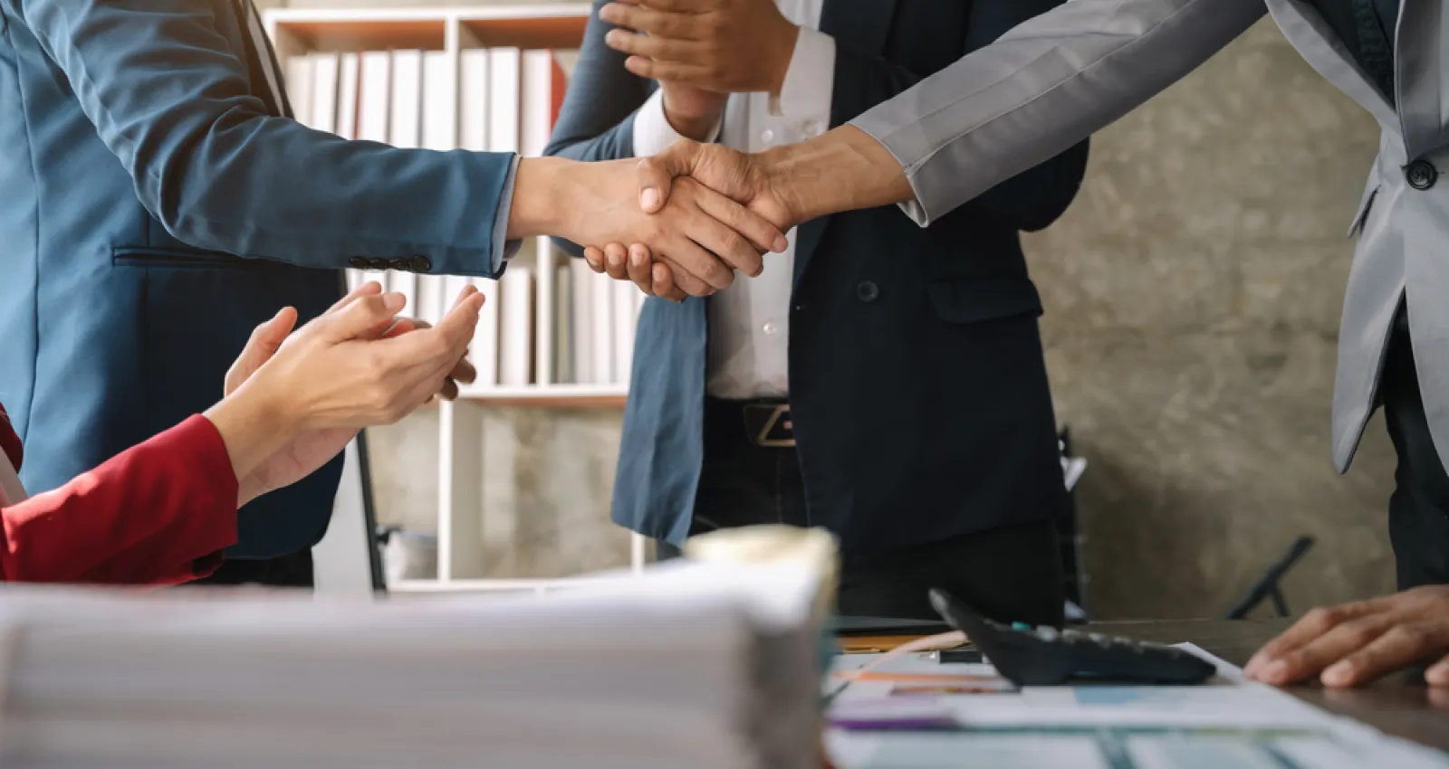 Foto de dos personas dándose la mano sobre una mesa