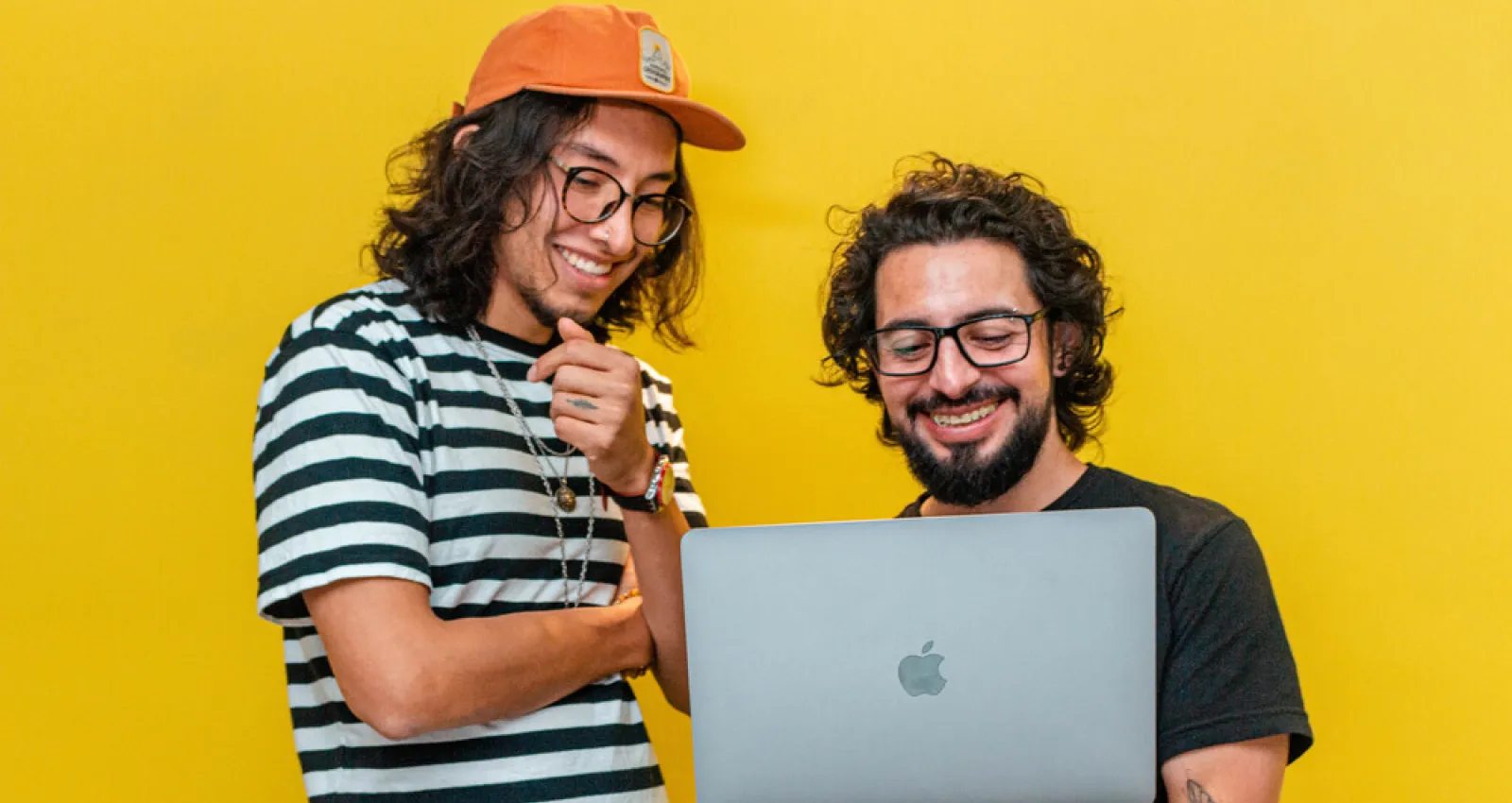 foto de dos personas mirando un pc con fondo amarillo