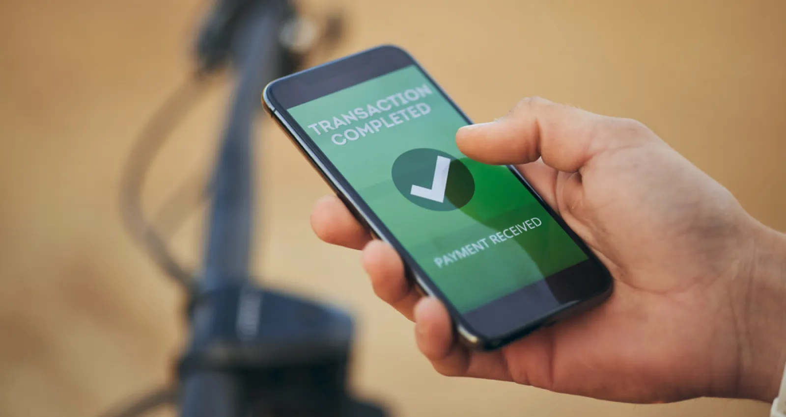 Foto de una mano sosteniendo un celular con una pantalla verde que dice transacción exitosa