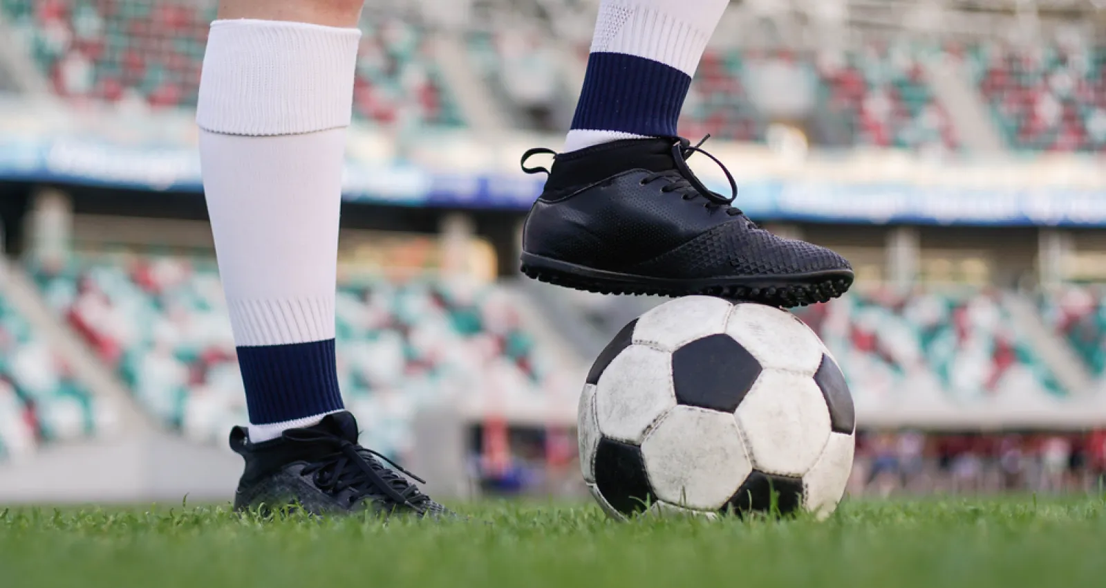 Foto de una persosona con guaybos y un balón de fútbol sobre su pie derecho
