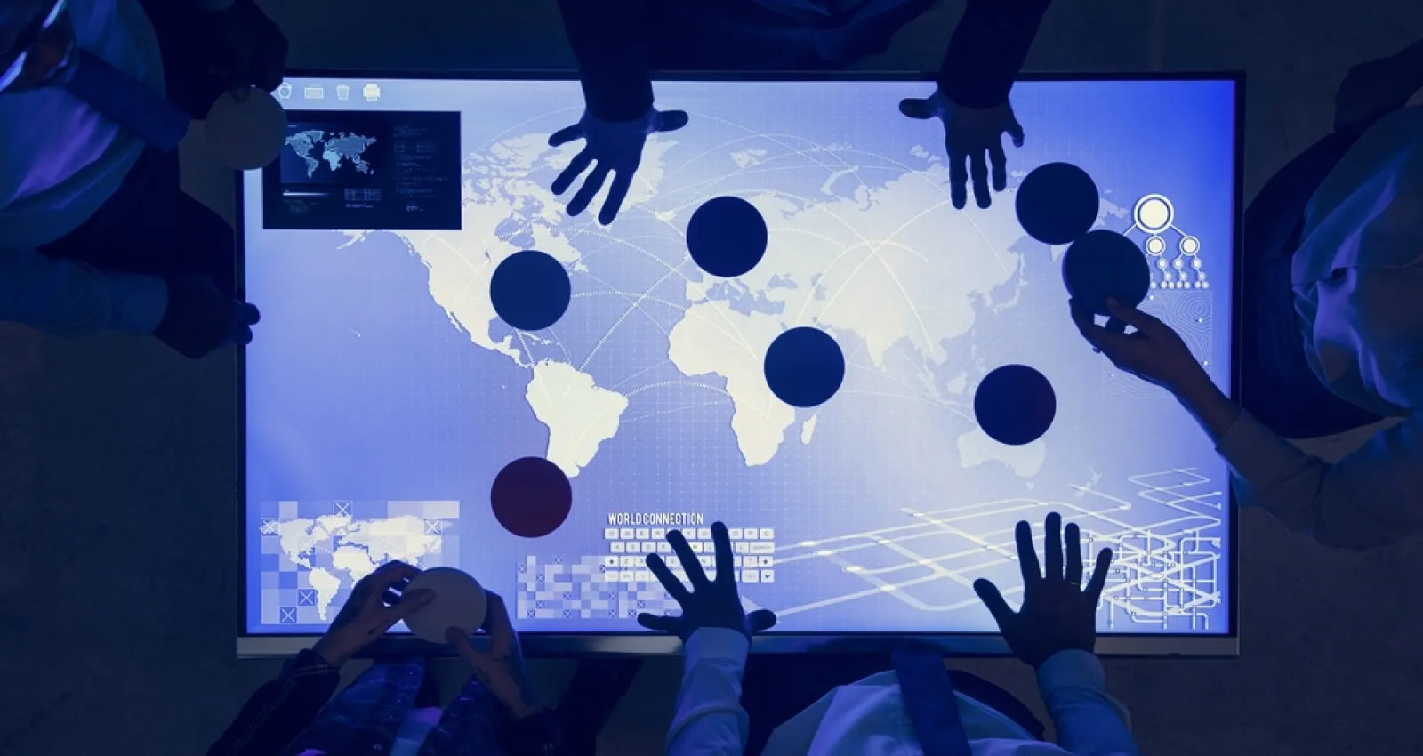personas reunidas sobre un tableto azul, solo se ve la silueta de las manos