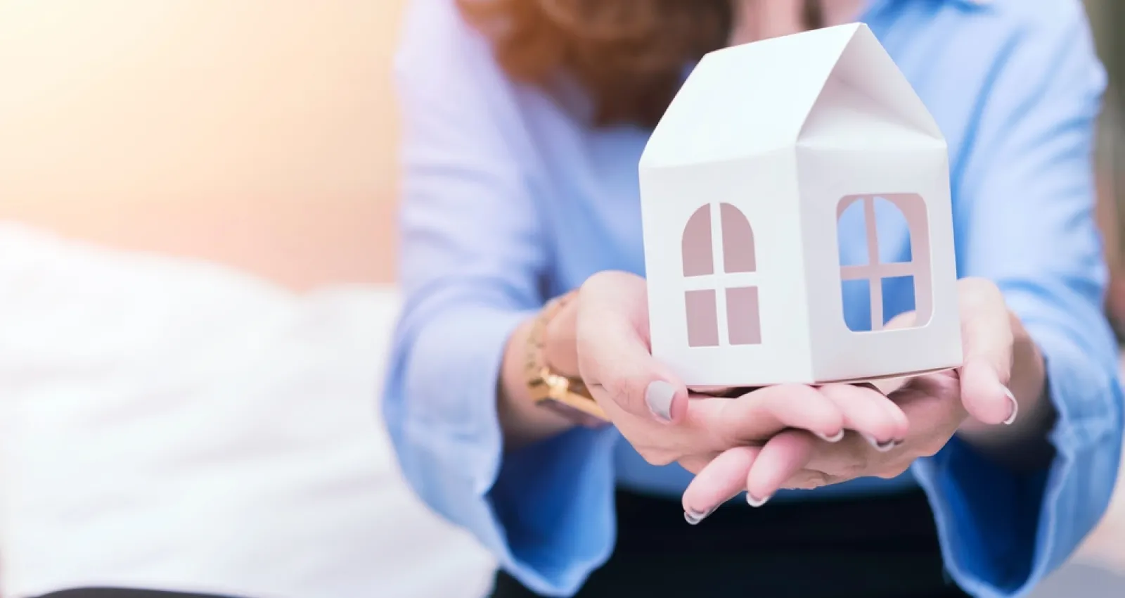 Representación de mujer con una casa en las manos.