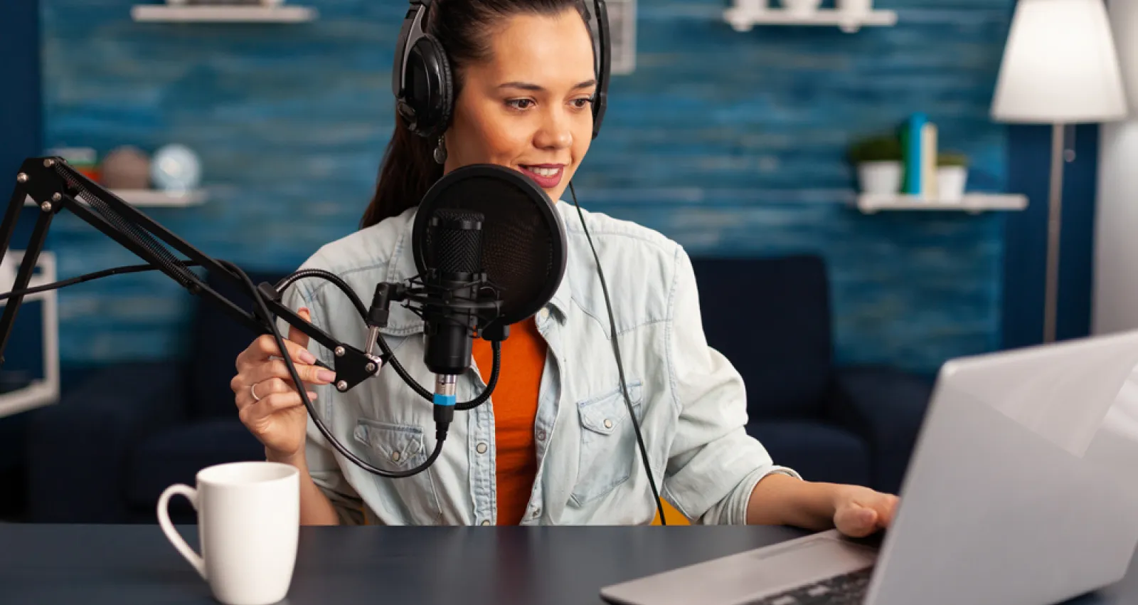 Foto de mujer hablando por micrófono al frente de un computador