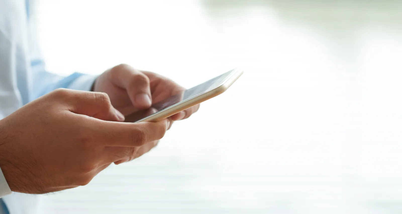 Una persona mirando su celular mientras lo sostiene con las manos