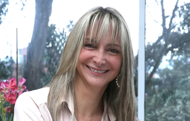 Mujer con cabello rubio sonriendo a la cámara