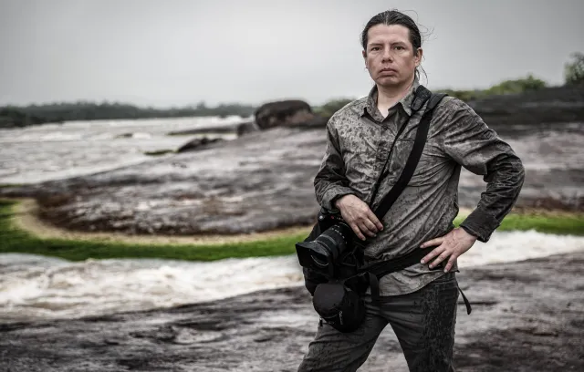Fotografía de una persona posando con un paisaje oscuro