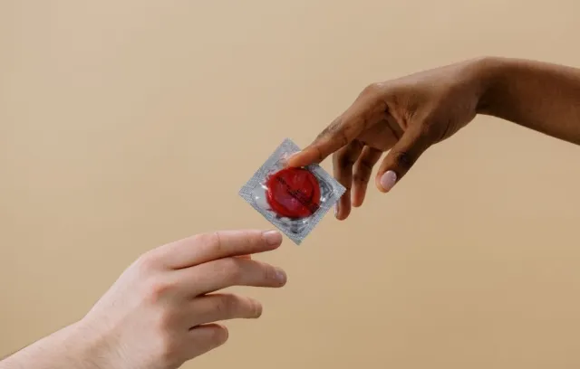 Foto de dos manos compartiendo un condón