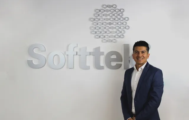 Foto de una persona con traje frente a un letrero de softtek